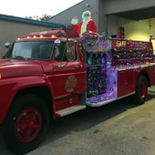 Santa waving from antique firetruck in front of fire house